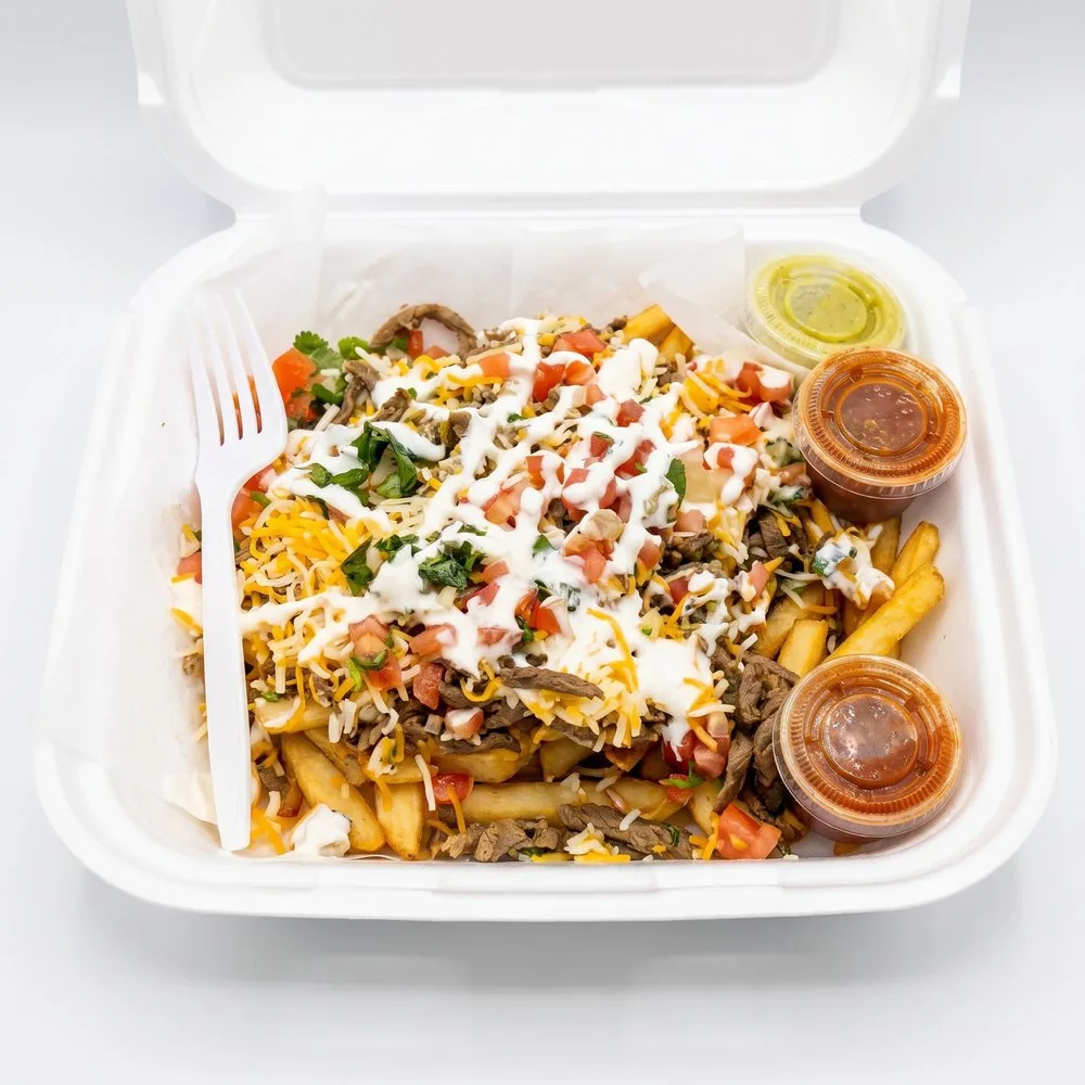 Loaded fries in a to-go box: fries, steak, cheese, pico de gallo, sour cream