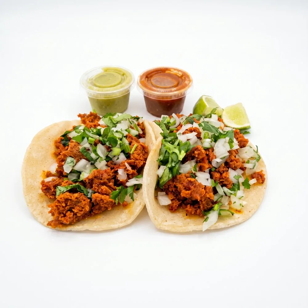 Chorizo tacos with onion and cilantro, salsa cups and lime