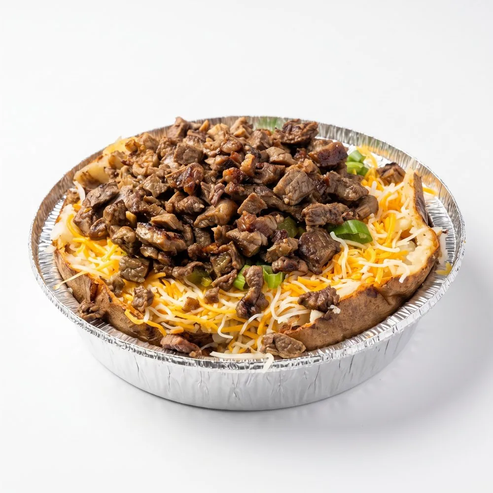 Loaded baked potato in a foil tray: steak, shredded cheese, green onion